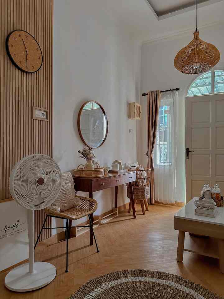 Natural wood tone and white-walled entrance living room space featuring rattan furniture and a round rug with cozy atmosphere.