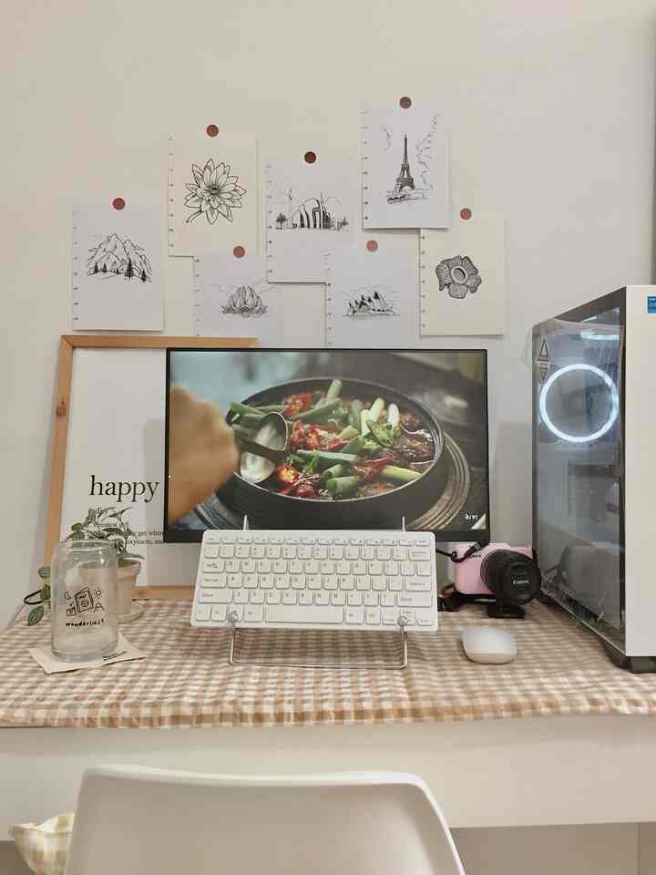 White and beige toned home office space featuring a computer, keyboard, and neat cozy desk setup