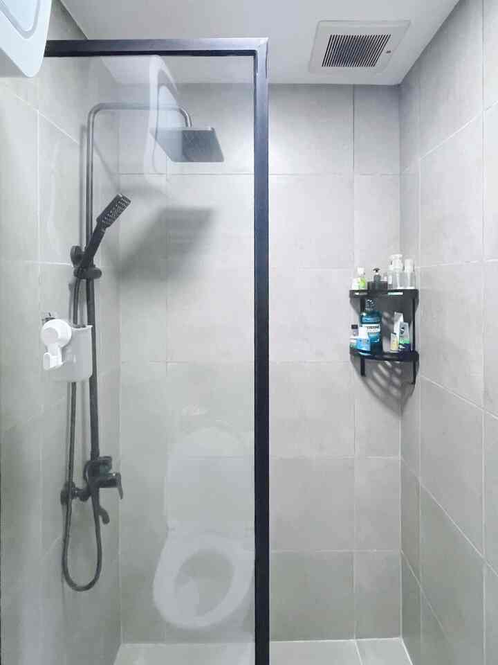 Black and gray toned bathroom featuring black metal frame partition, shower fixtures, and wall-mounted shelf in a modern space