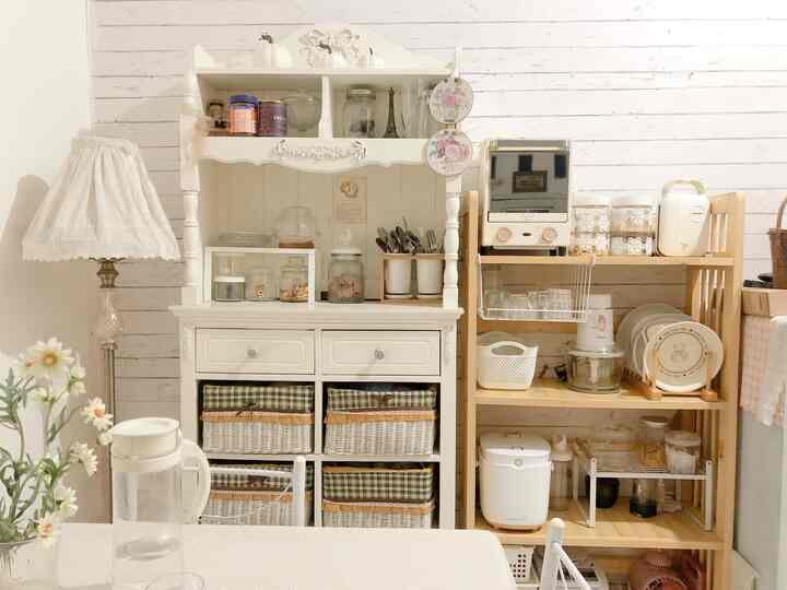 Cozy two-person dining room featuring white and wood tones, organized storage baskets, and vintage-style lamp creating warm atmosphere
