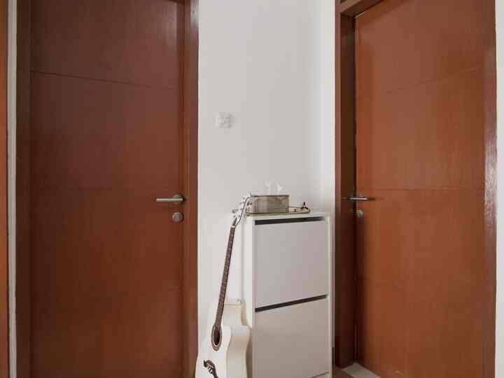 Simple entrance featuring a white shoe cabinet between white walls and brown wooden doors