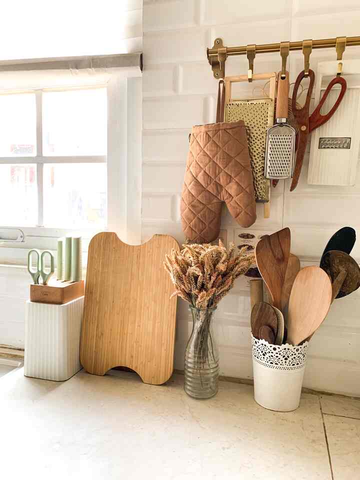 Bright and cozy kitchen with white tiled walls and wood tone kitchen utensils arranged neatly