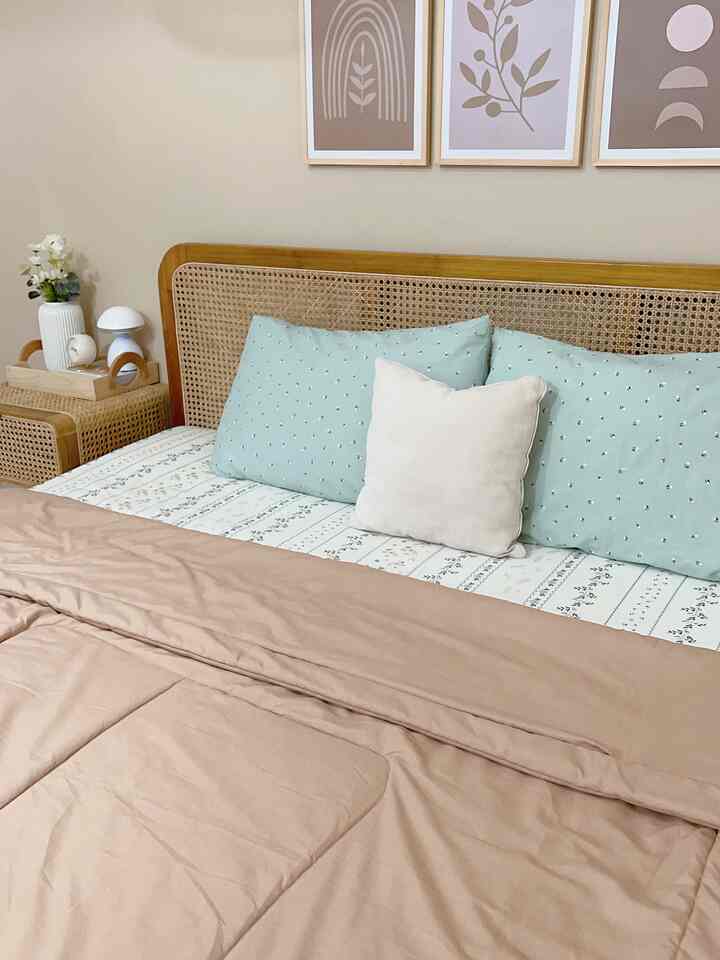 A natural modern bedroom in beige and wood tones featuring a rattan bed and mint cushions, creating a cozy atmosphere