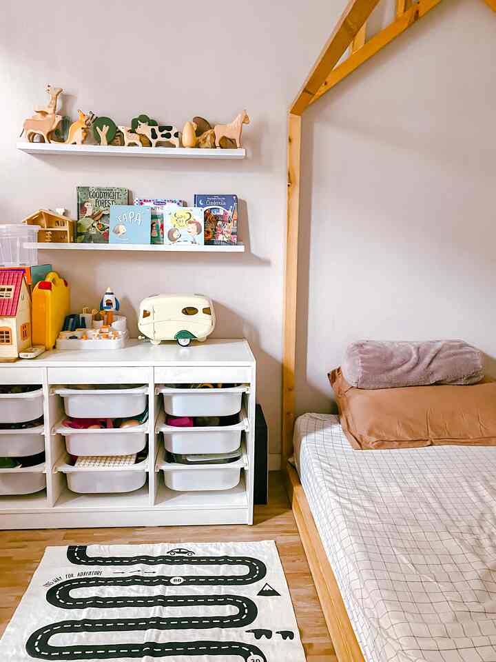 Natural wood tone and white kids' room featuring toy storage and a bed frame with a cozy atmosphere