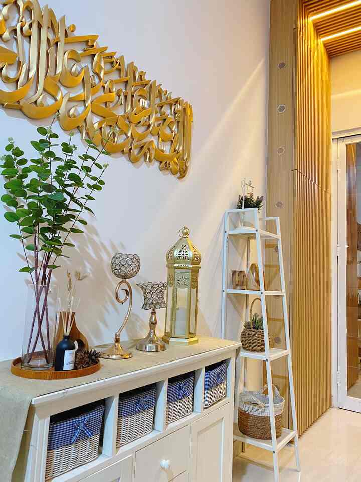 White and gold toned living room featuring storage cabinet, decorative objects, and plants with a cozy atmosphere