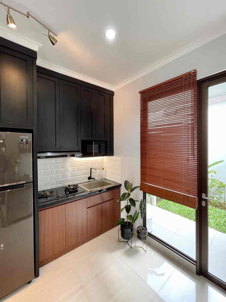 Dapur dan teras belakang dibatasi sekat berupa bukaan jendela kaca dan pintu kaca. Material kaca yang dipakai pada sebagian pembatas ruangan membuat cahaya matahari bisa lebih banyak masuk ke dalam ruangan - pagi dan siang. 

Elemen kayu bisa ditemukan di berbagai sudut rumah. Mulai dari tirai bukaan jendela, bangku teras belakang, bagian langit-langit ruangan, dan sejumlah furnitur. Elemen kayu dengan warna dan tekstur naturalnya (lagi-lagi) dibuat lebih personal karena dikombinasikan dengan material-material warna hitam. Keberadaan kayu melenyapkan kesan kaku dari warna hitam sekaligus memberi nuansa hangat di sekelilingnya. 

#rumahmungil
#personalizedfurniture 
#dapurmungil
#customkitchenset
#arsitekturtropis
#naturaldesign
#moderncontemporary
#homedecorinspo
#roomdecorinspo
#aesthetichomedecor