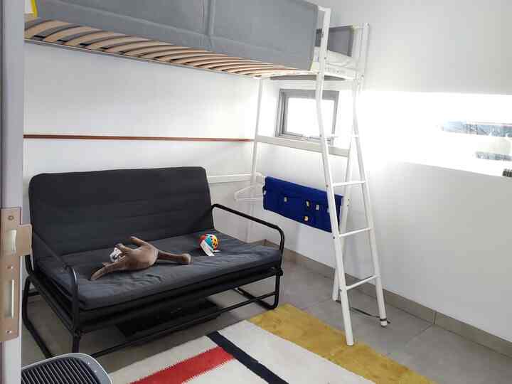 White and gray toned kids' room featuring a convertible sofa bed and bed frame for practical use