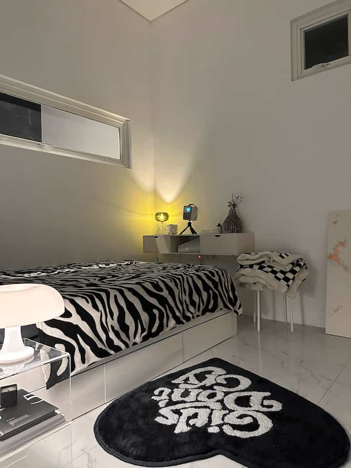 Small bedroom in white and black monotone colors, featuring zebra pattern bedding and minimalist furniture