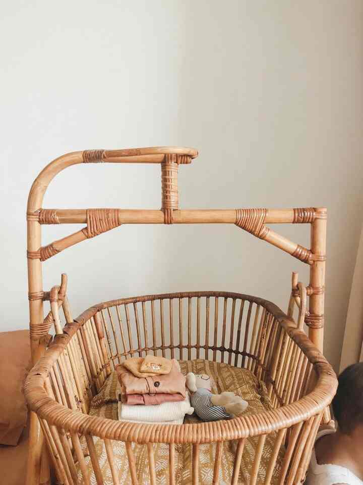 Beige-toned walls and natural rattan baby crib placed in cozy bedroom space