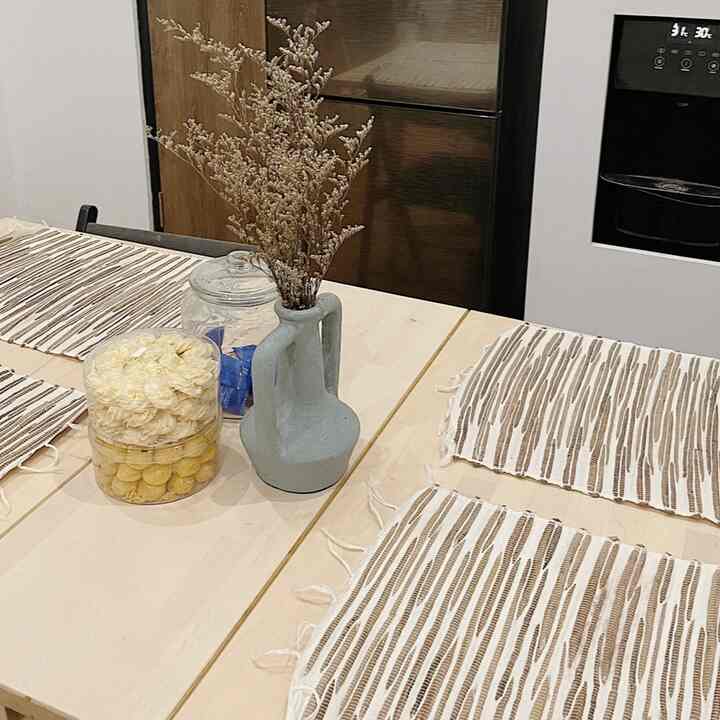 Beige-toned kitchen dining table featuring a natural-colored vase with dried flowers and simple snacks in a neat setting