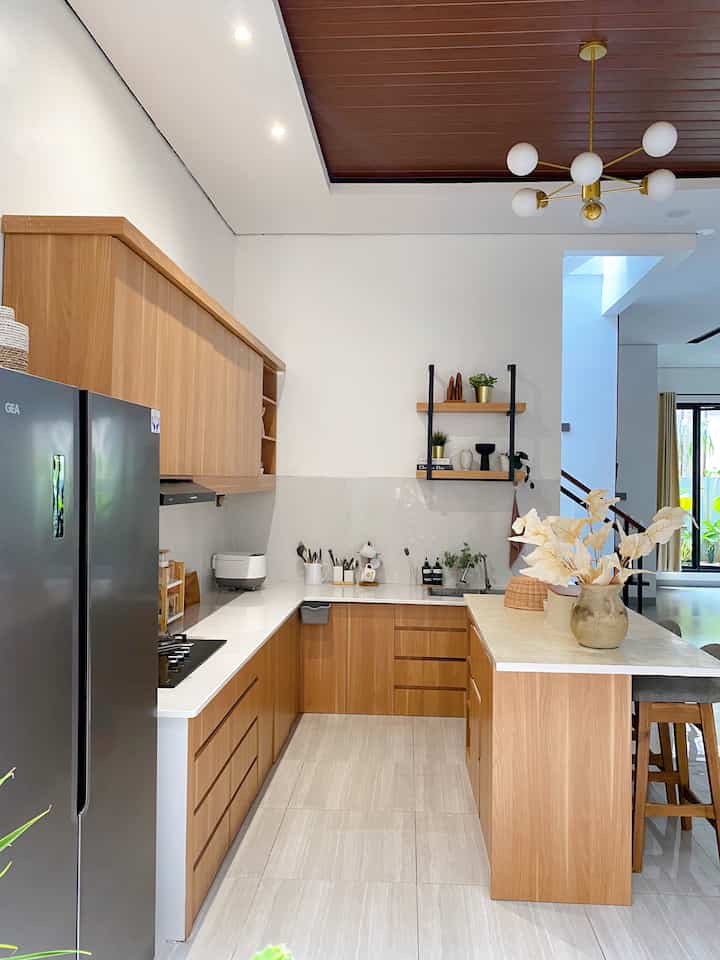 Modern kitchen with white walls and wood-tone cabinets, featuring kitchen island and shelves with decorative items