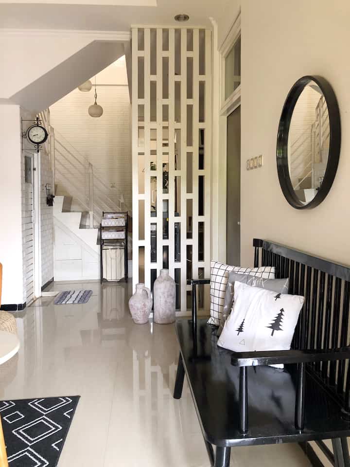 White and black toned living room featuring an open room divider and black bench, creating a simple and tidy interior