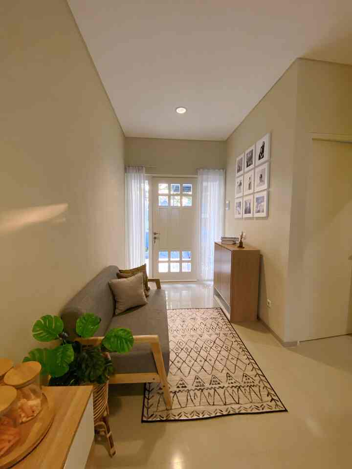 Beige walls and wood-toned furniture in a long narrow natural modern living room featuring a gray sofa and patterned carpet creating a cozy atmosphere