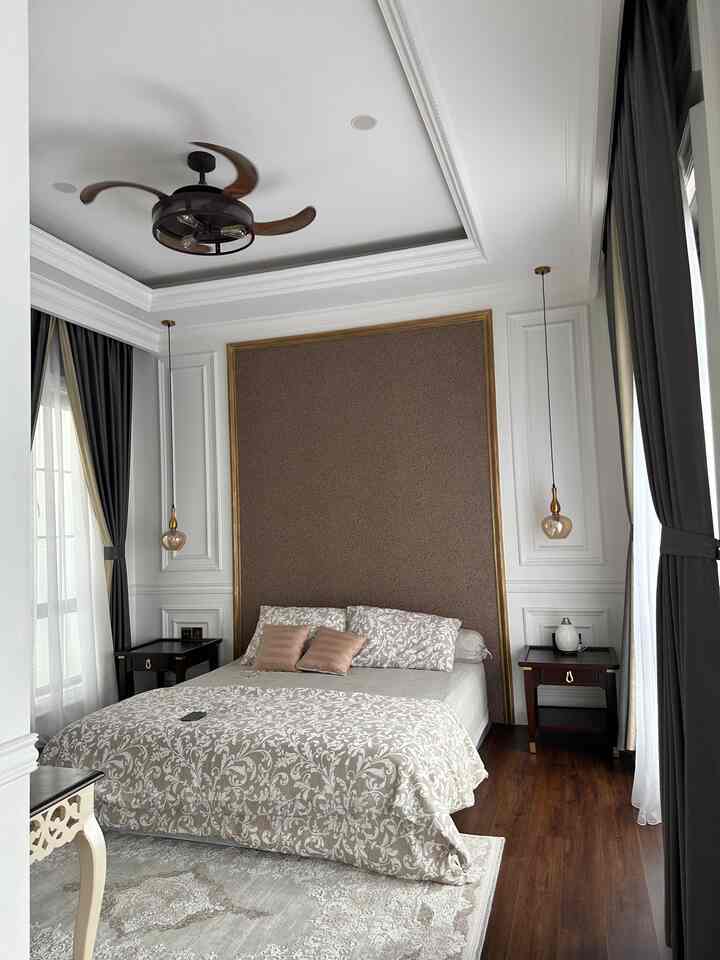 Classic bedroom with white ceiling and wood tone floor, patterned bedding and nightstands centered, featuring a vintage ceiling fan and warm ambiance