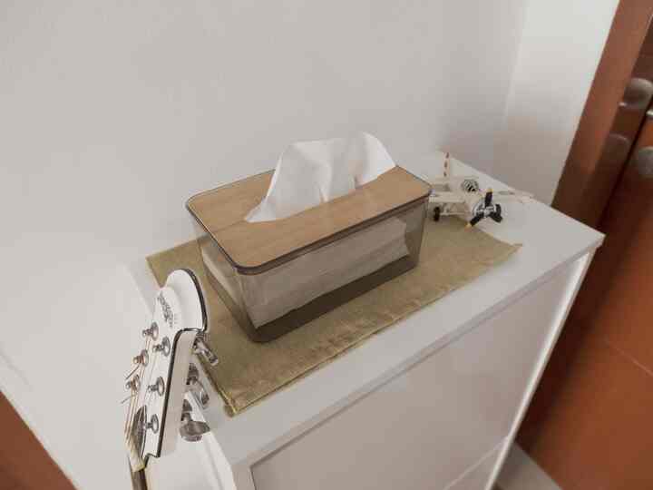 Bright white and natural tones in an entrance cabinet area topped with a tissue box and model airplane, showcasing a tidy space