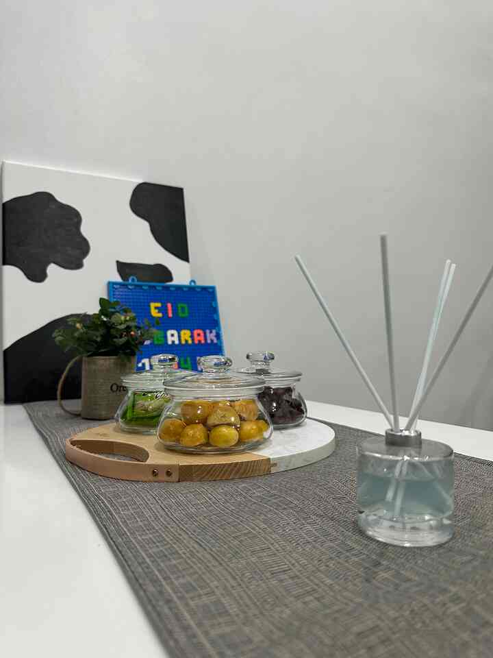 Minimal dining room in white and gray tones, featuring a dining table with glass jars of nastar cookies on a tray at the center
