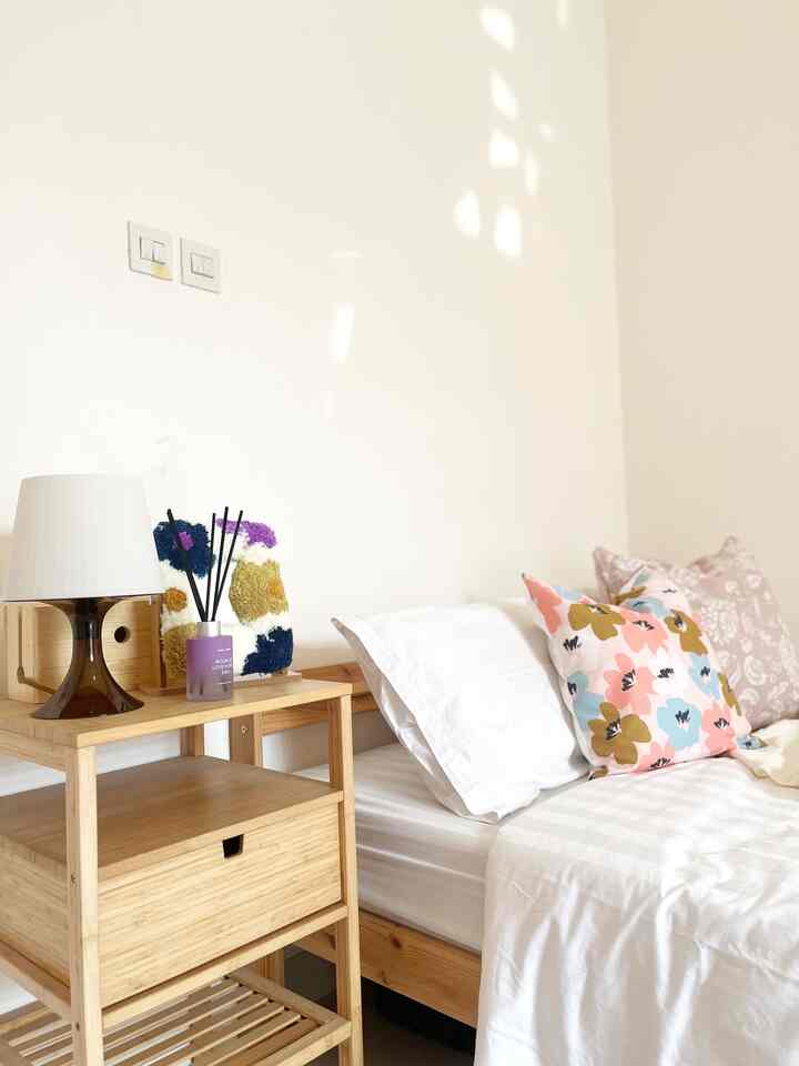 White and wood tone kids' bedroom featuring cozy bed with floral pillows and diffuser on nightstand