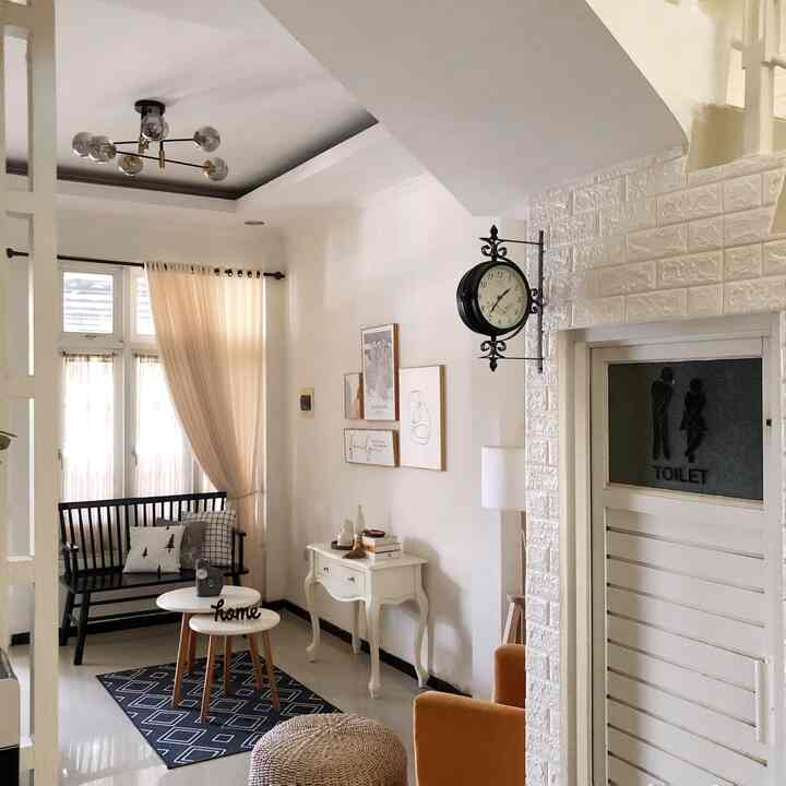 White and black toned living room featuring a black bench, white console table, and vintage wall clock in a simple setting