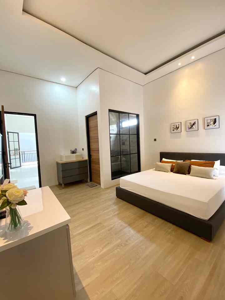 Modern bedroom with dominant white and wood tones, featuring a large bed and simple furniture creating a cozy atmosphere