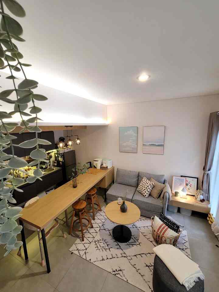 Natural modern-toned living room and kitchen connected in a cozy space featuring wooden tables and a minimalist sofa