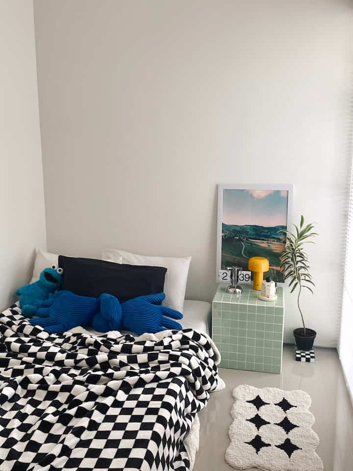 White and black monotone bedroom featuring checkered bedspread and yellow table lamp, sleek and simple atmosphere