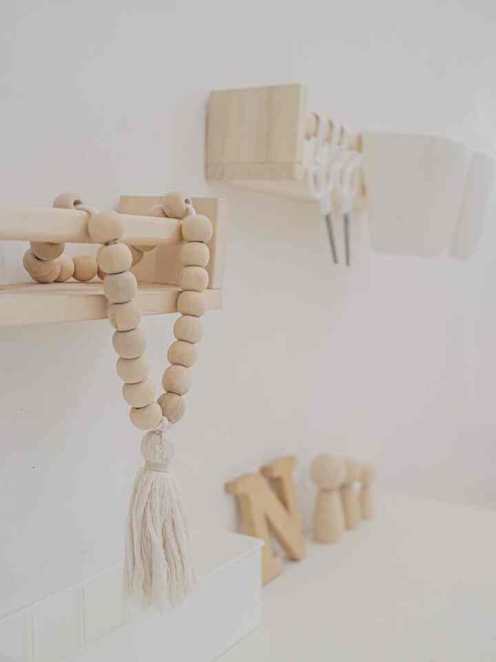 A kids' room in white and wood tones featuring wooden storage and DIY posters creating a neat atmosphere