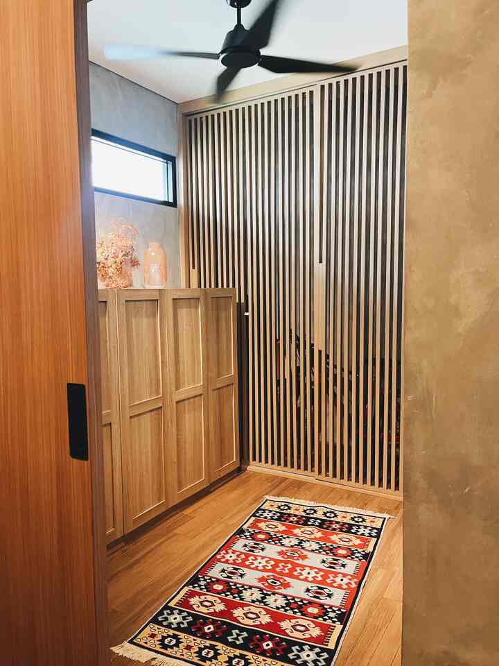 Beige and wood tone entrance space with shoe cabinet and patterned rug, creating a warm, inviting atmosphere