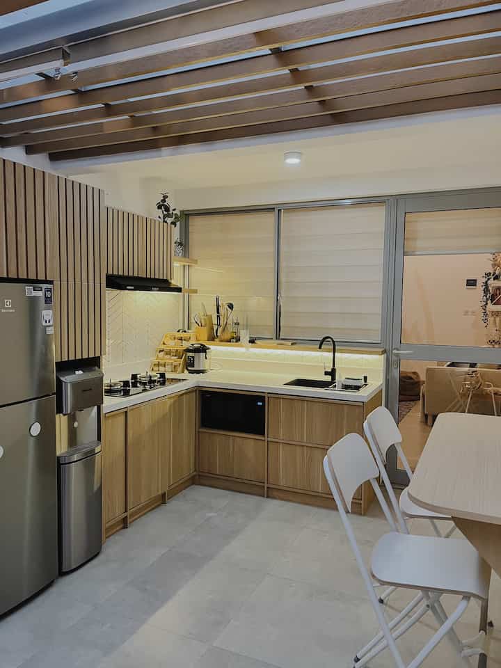 Natural-toned kitchen space featuring wooden kitchen set and white dining chairs in a clean dining room