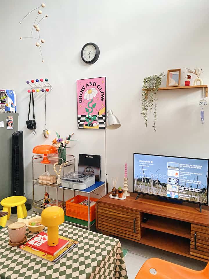 Compact mid-century modern living room with white walls and vibrant orange and yellow furniture accents
