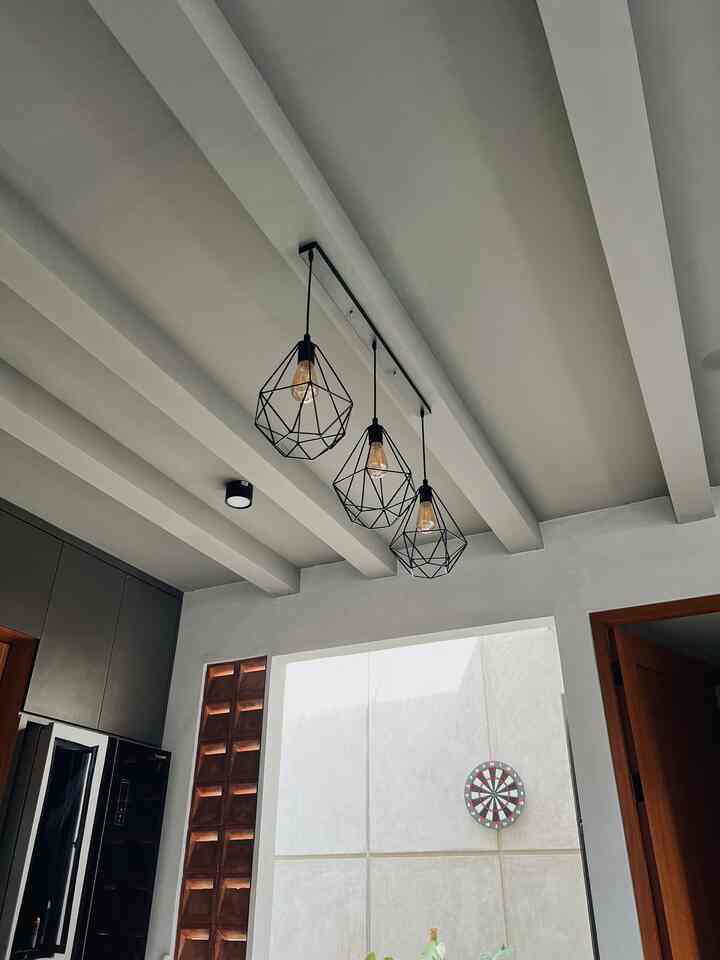 Gray-toned exposed ceiling with black pendant lights in a monotone kitchen featuring subtle wood tone accents in industrial Japandi style