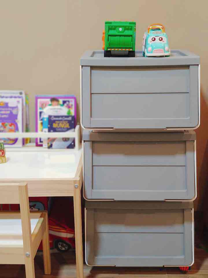 Natural color kids' room with beige walls, wooden furniture, and gray storage drawers topped with toys creating a neat and cozy space