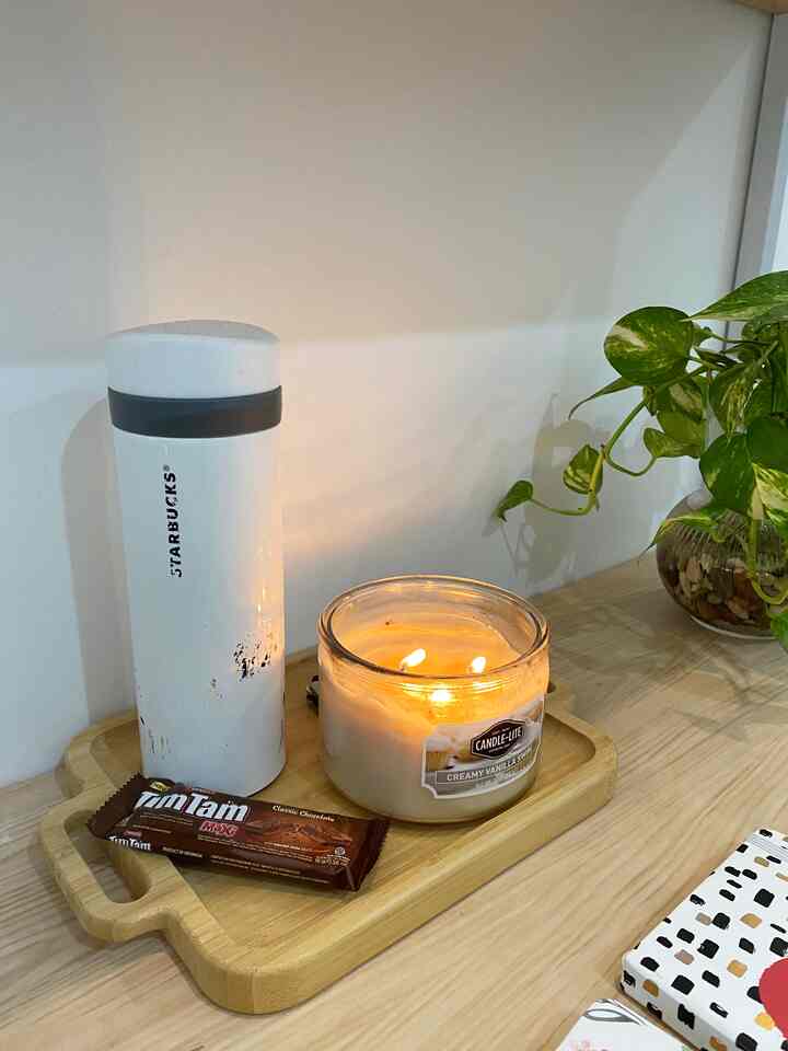 White and wood tone home office featuring aroma candle, plant, and coffee tumbler with a warm, focused atmosphere