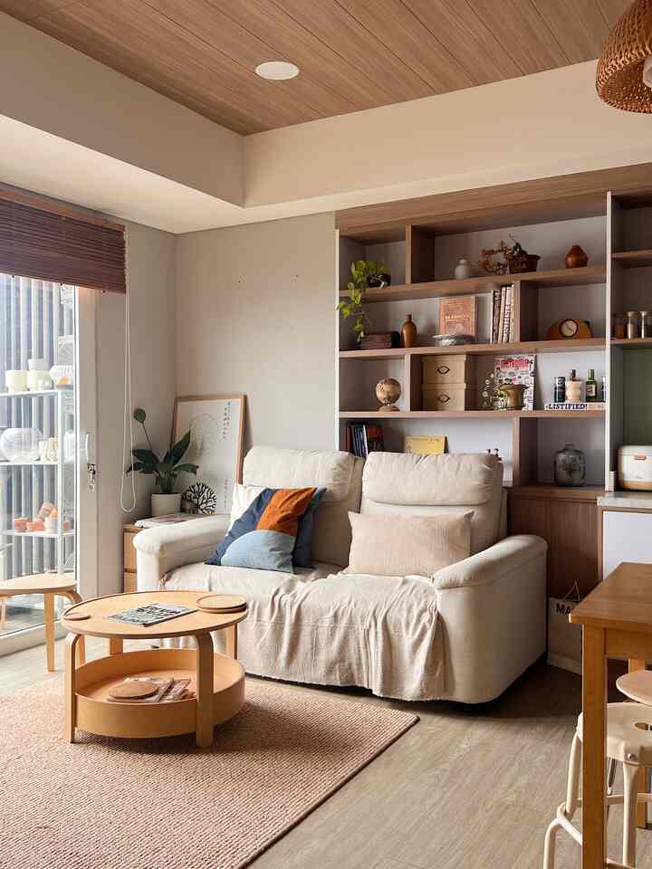 Beige and wood tone living and kitchen area featuring natural furniture and cushions with a cozy atmosphere