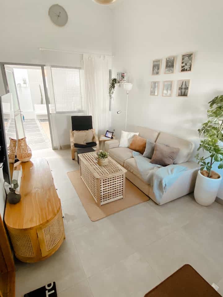 Compact living room in white and wood tones featuring beige sofa and wooden coffee table with cozy ambiance