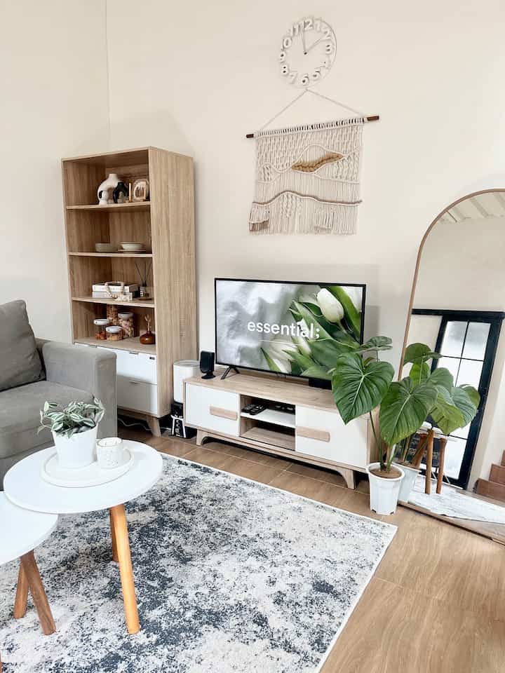 Natural wood tones and neutral colors characterize the 4.3x3 meter living room featuring a sofa, TV stand, and plants creating a cozy atmosphere