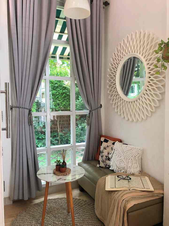 Natural style cozy entrance with gray curtains, small round table, sofa with cushions, and decorative mirror