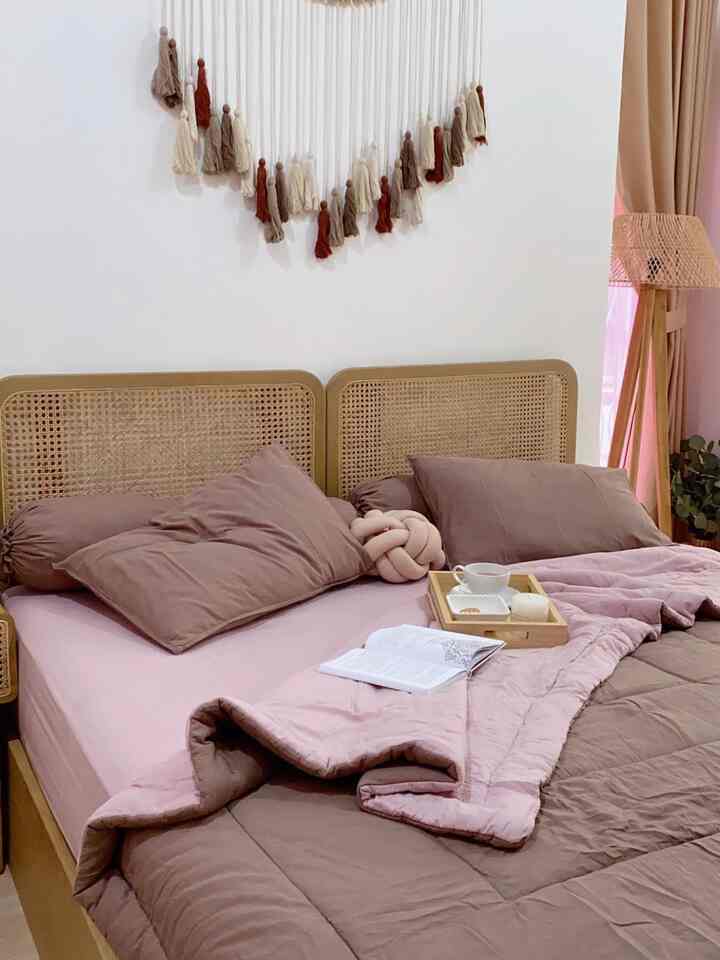 Cozy bedroom in natural brown and pink tones featuring rattan bed and comfortable bedding
