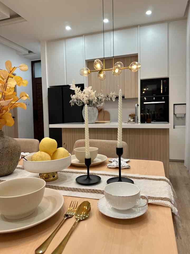 White and wood-tone kitchen and dining room featuring fabric dining chairs and gold accessories in a simple, natural space