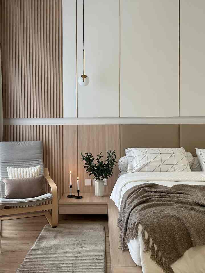 Natural beige and wood tone bedroom featuring a cozy bed and armchair with a simple, calming atmosphere