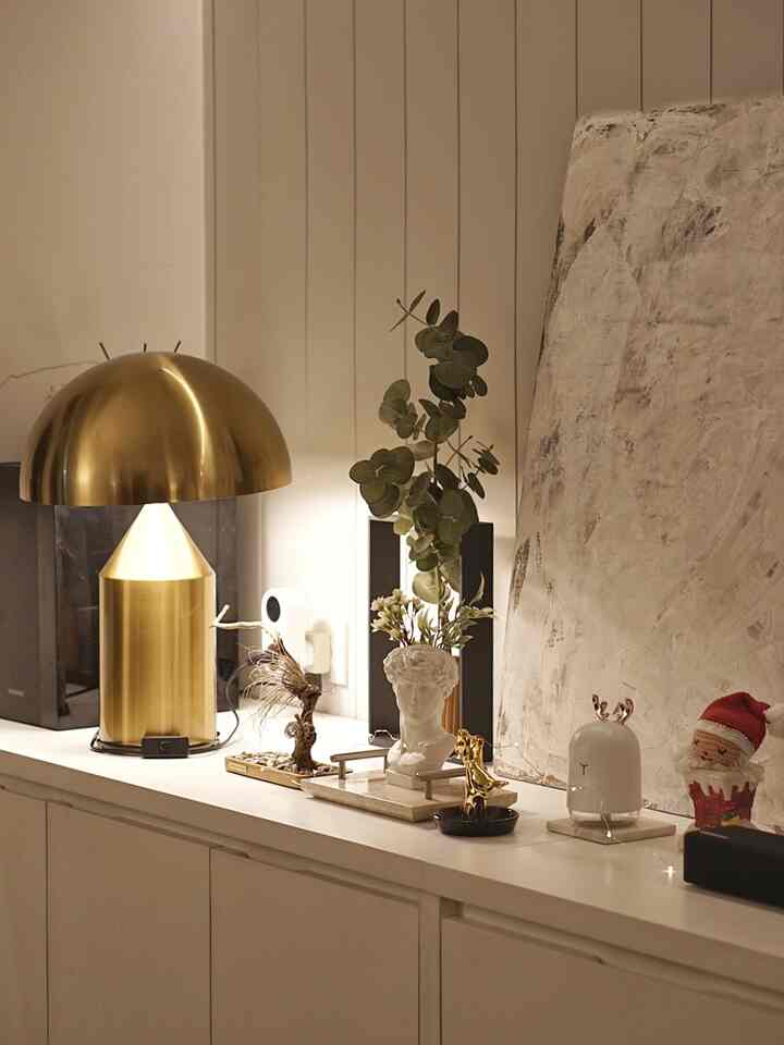 Natural-toned home office space featuring white cabinets and gold lamp with cozy ambiance