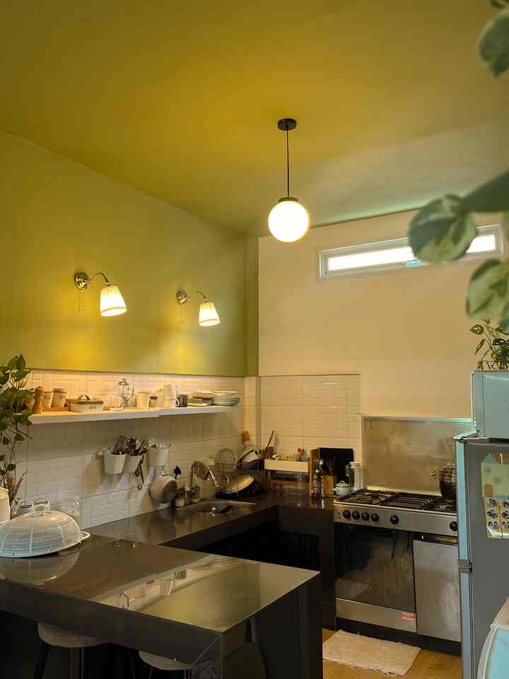 Mid-Century Modern kitchen with green ceiling and walls, black counters, and wall sconces shaping a cozy space
