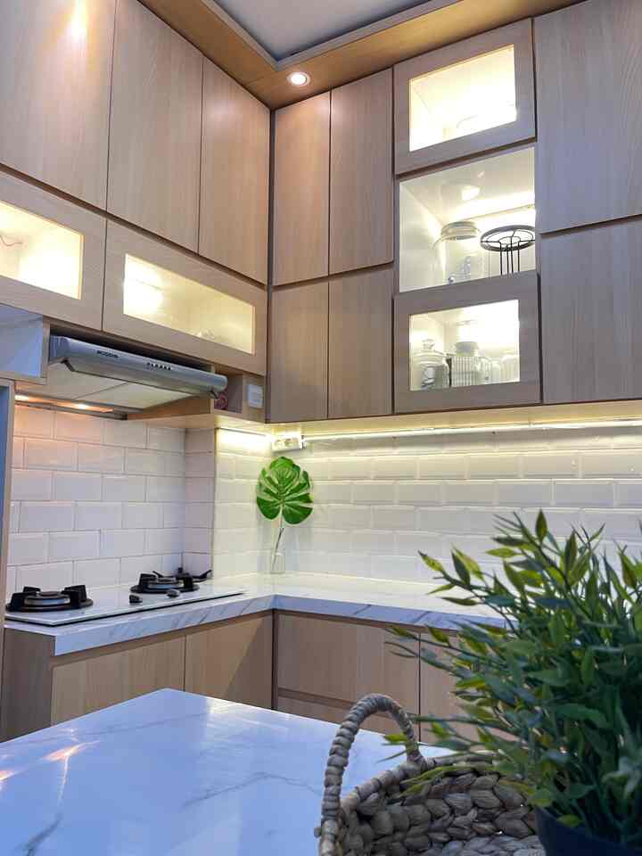 Beige and white toned kitchen featuring wooden cabinets and a monstera leaf, presenting a clean and natural atmosphere