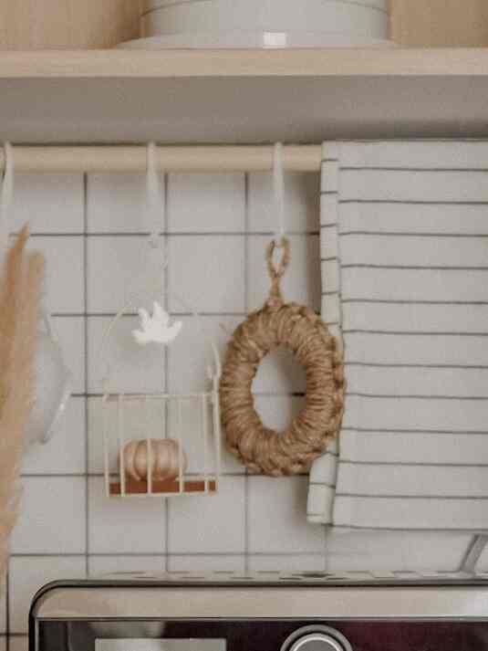 White tiled kitchen corner featuring hanging towels and natural-toned decor creating a cozy atmosphere