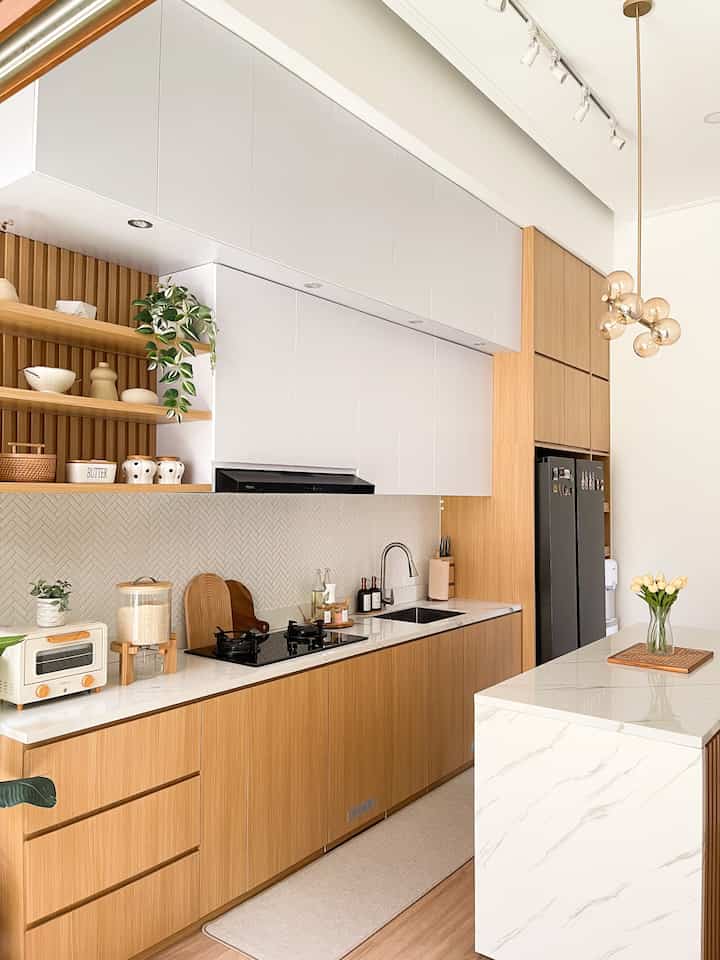 Styling Dapur Agar terlihat Cantik dan rapi

Dapur adalah jantung rumah, karena fungsinya yang sangat penting dalam proses mengolah masakan untuk seluruh anggota keluarga. 
Jadi setuju kan, pentingnya mewujudkan dapur yang bersih, rapi dan juga teratur demi menjaga kesehatan keluarga. Cara yang aku lakukan untuk styling dapur agar terlihat cantik, rapi dan teratur antara lain :
1. Memperhatikan kombinasi warna sesuai konsep dapur. Karena dapur ini berkonsep/ bertema japandi, maka aku pilih warna-warna terang seperti putih dan wood (warna kayu). Warna putih juga akan memberi kesan ilusi optikal agar ruangan terlihat lebih lua dan terang. 

2. Perbanyak rak penyimpanan / kabinet kitchen set 
Agar dapur tetap rapi, biasanya aku menyimpan peralatan dapur di dalam kabinet tertutup. Alat makan, peralatan memasak, bumbu dapur, bahan makanan semua disimpan di dalam kabinet. Jadi dapur tetap rapi dan tidak penuh dengan barang- barang. 

3. Selalu Menjaga Kebersihan Dapur Setelah Selesai Digunakan. Setelah selesai memasak, dapur segera dibersihkan dan dirapikan kembali. Usahan untuk tidak menumpuk piring kotor, agar dapur tidak bau dan terlihat betantakan. 

4. Pajang Barang Dekorasi yang menarik
Pasang ambalan untuk tempat meletakkan barang dekorasi seperti vas bunga, tanaman juntai palsu atau teko. Tidak lupa juga menambahkan lampu Led strip di area bagian atas   Top table sebagai pencahayaan. 

Vocal Point di area dapur @rumahnayyara20 adalah Backsplash. Untuk backsplash, menggunakan keramik motif herringbone glossy white.

Aku juga menambahkan tanaman pisang artificial agar dapur menjadi lebih hidup dan segar. Walaupun palsu, tanaman pisang ini seperti tanaman asli yang dapat menarik perhatian. 


#kitchenstyling #kitchendecorideas #kitchenmakeover #kitchenwhiteandwood #kitchendesign
