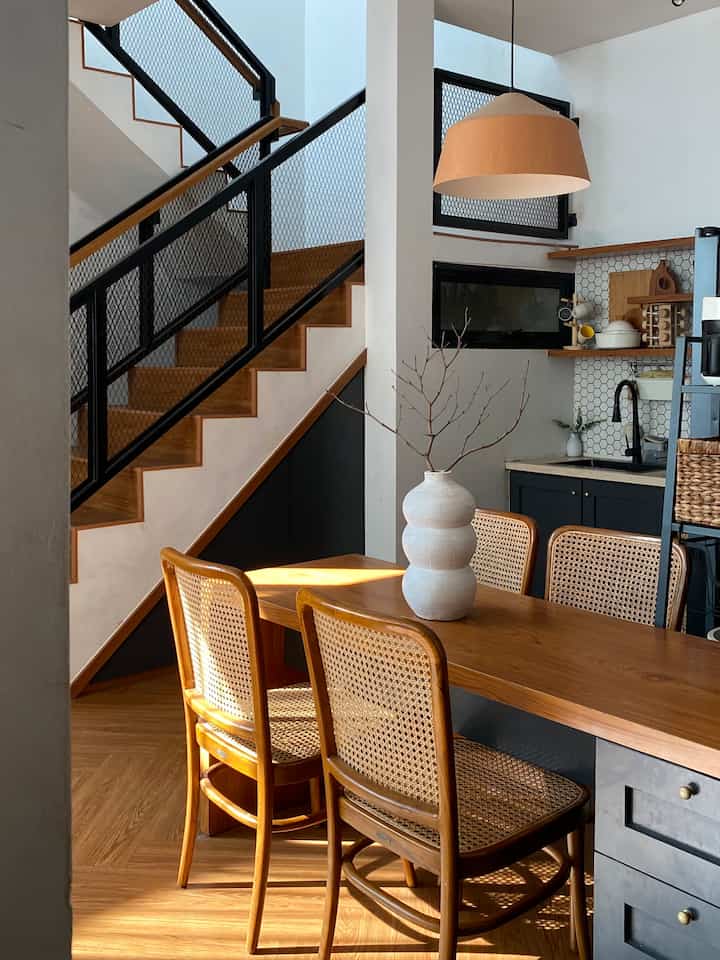 Brown wood tones and white walls harmonize in a kitchen dining space featuring mid-century modern and Japandi styles