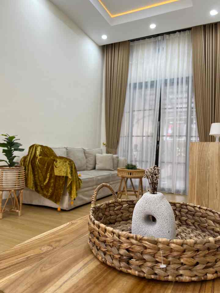 White and brown toned living room featuring wooden furniture and rattan accents with a bright, clean atmosphere