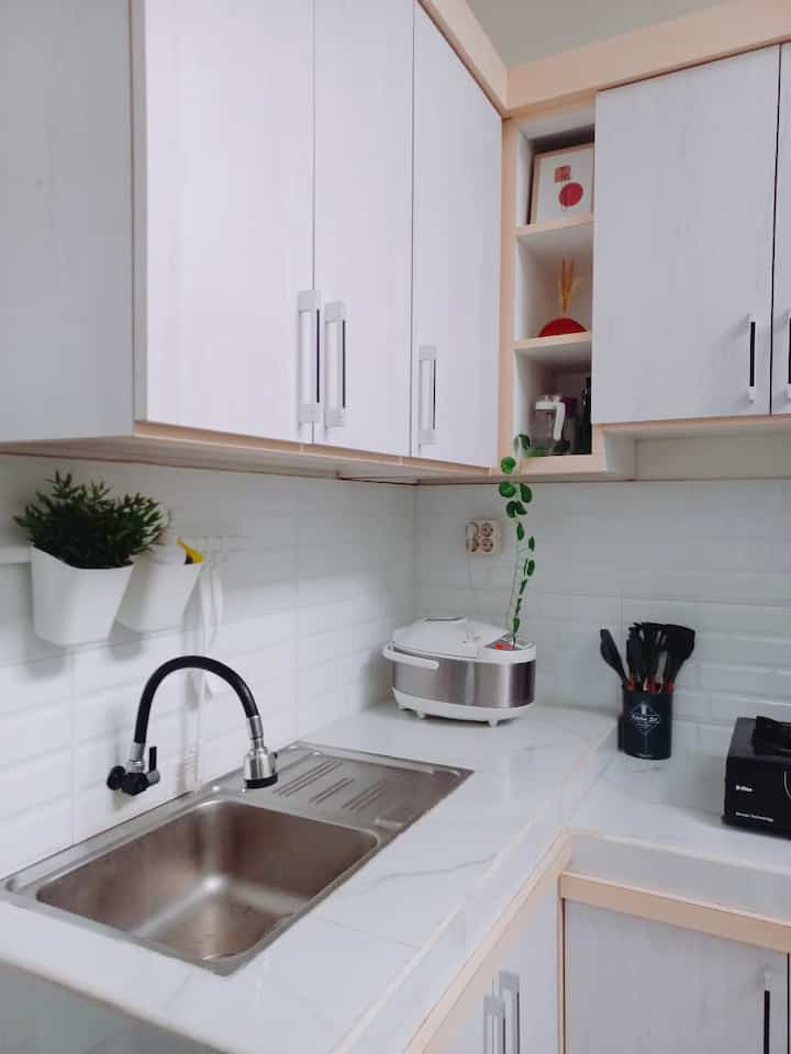 Minimal white-toned compact kitchen featuring upper and lower cabinets with a clean, organized interior