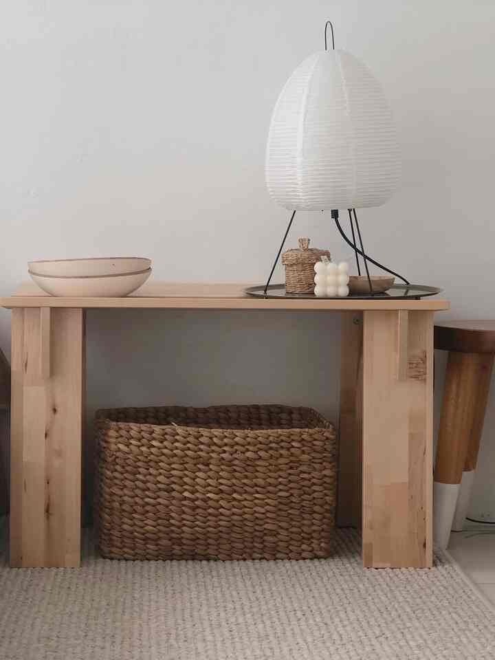 Natural-toned living space featuring a wooden table and woven basket with an Akari lamp creating a warm atmosphere