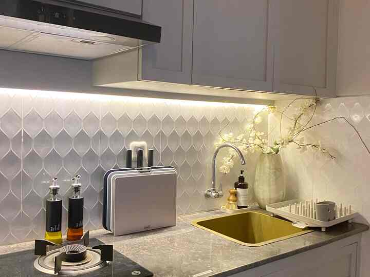 Modern kitchen in bright white and gray tones featuring a gold sink and clean lighting creating a minimal atmosphere