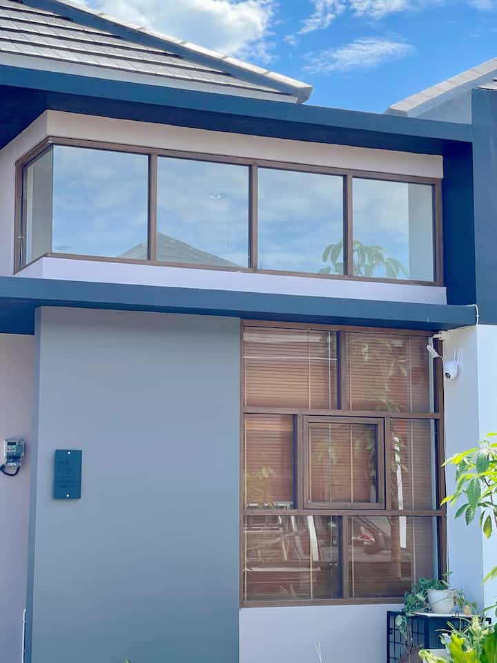 Gray and wood-toned Japandi style detached house facade featuring large windows and entrance with clean modern design